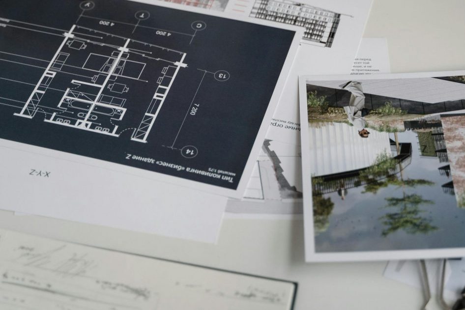 Architect hands reviewing architectural blueprints and design documents in an office setting.